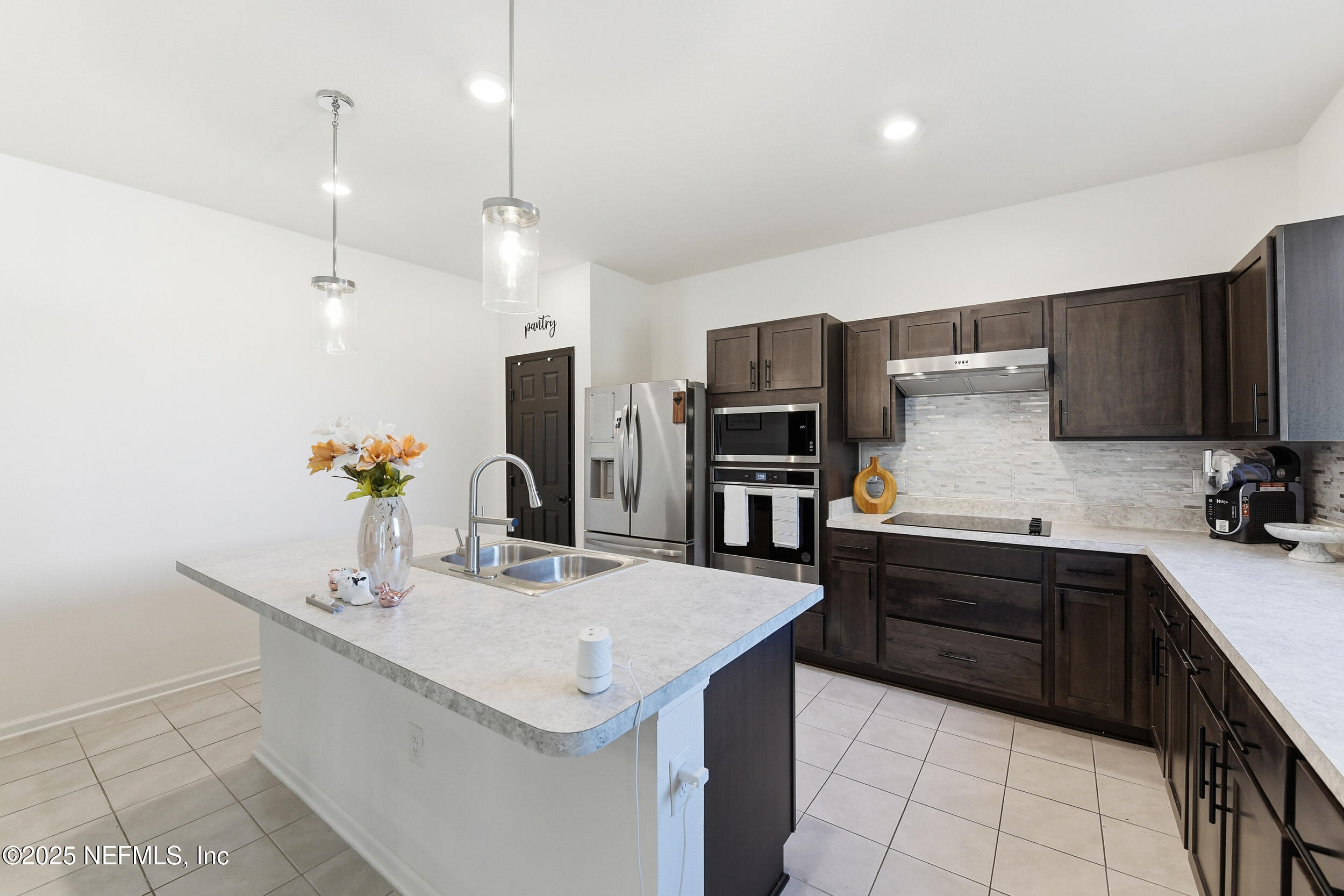11183 Stapleton Drive Jacksonville, FL 32222 - Photo 5 of 43 a kitchen with a sink a kitchen island a stove a refrigerator and a sink with wooden cabinets