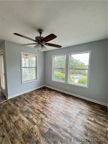 an empty room with windows and ceiling fan