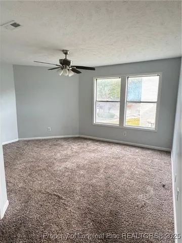an empty room with windows and fan