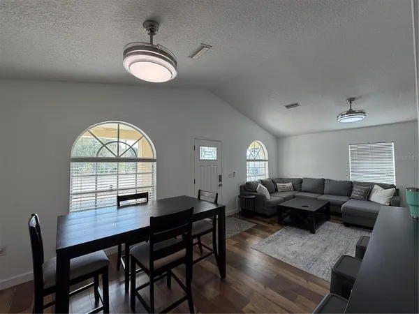 a living room with furniture a large window and a dining table