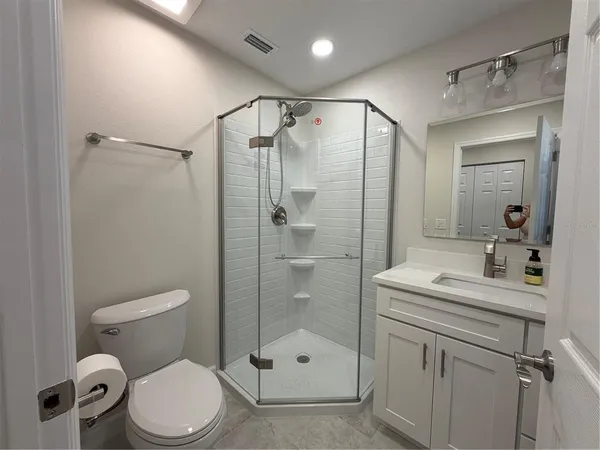 a bathroom with a shower sink vanity mirror and toilet
