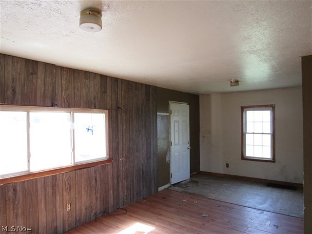 3845 Bower Road Rootstown, OH 44272 - Photo 3 of 20 Empty room featuring wooden walls, a textured ceiling, and dark hardwood / wood-style flooring