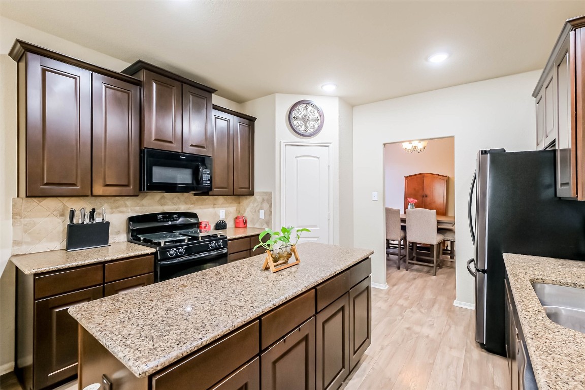 4718 Sedgewood Drive Rosenberg, TX 77471 - Photo 7 of 23 a kitchen with stainless steel appliances granite countertop a refrigerator a stove top oven a sink dishwasher and wooden cabinets with wooden floor