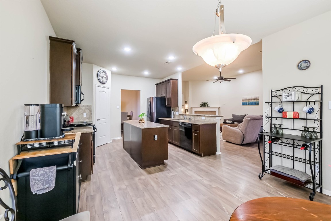 4718 Sedgewood Drive Rosenberg, TX 77471 - Photo 9 of 23 a kitchen with stainless steel appliances kitchen island granite countertop a refrigerator oven a sink a dining table and chairs with wooden floor