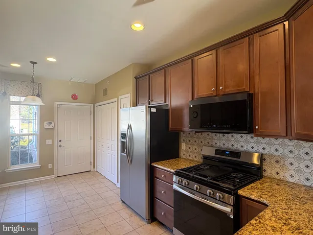 a kitchen with stainless steel appliances granite countertop a stove a refrigerator and a microwave