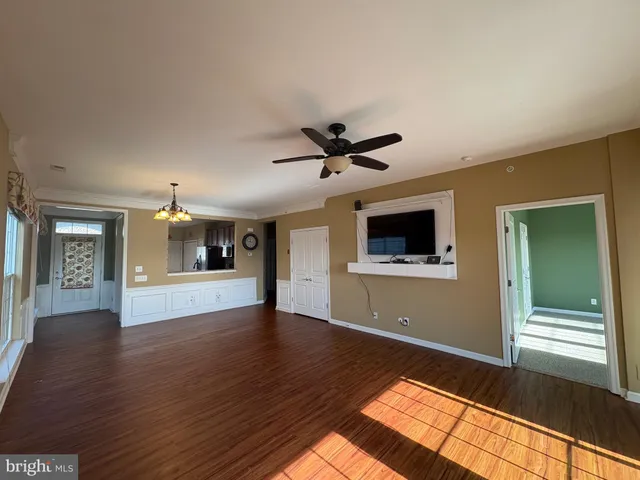 a view of empty room with wooden floor and fan