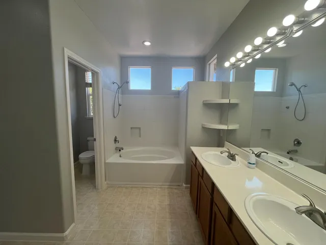 a bathroom with a tub sink double vanity and mirror