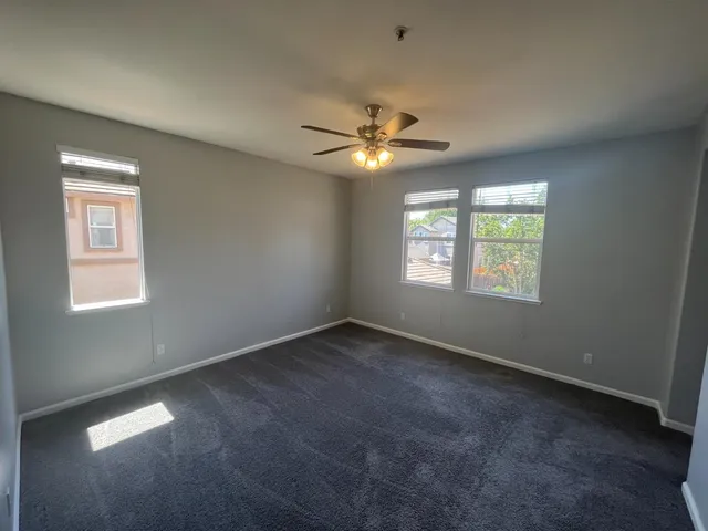 an empty room with a window and a fan