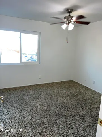 an empty room with a window and a fan