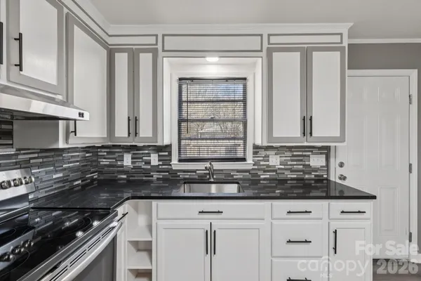 a kitchen with granite countertop a sink stove and cabinets