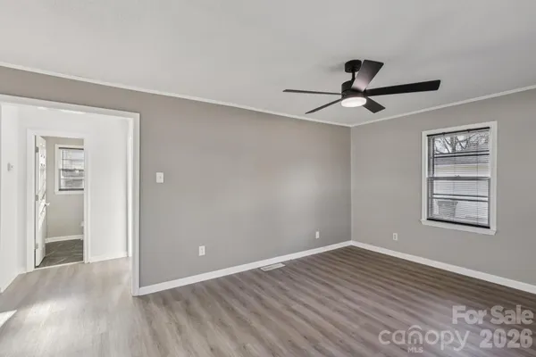 a view of empty room with wooden floor and fan
