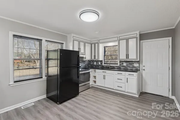 a kitchen with granite countertop a refrigerator stove top oven and sink