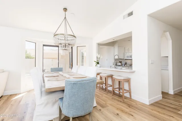 a dining room with wooden floor a chandelier a wooden table and chairs