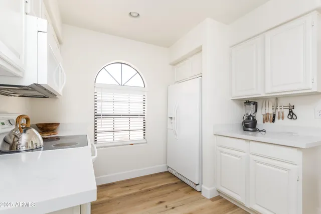 a kitchen with white cabinets and a window