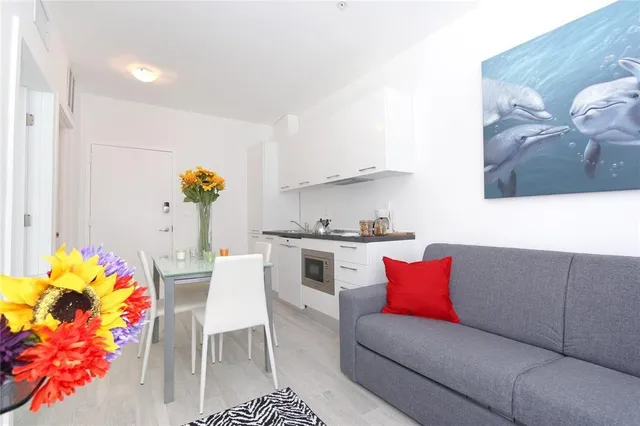 a living room with furniture flowerpot and a kitchen view
