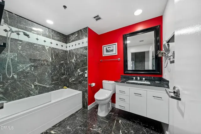 a bathroom with a granite countertop sink mirror vanity and toilet