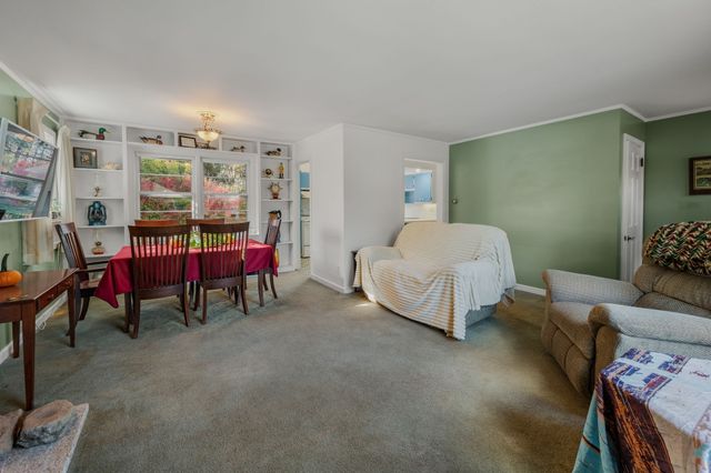 a living room with furniture and a dining table with bookshelf