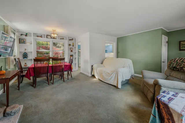 a living room with furniture and a dining table with bookshelf
