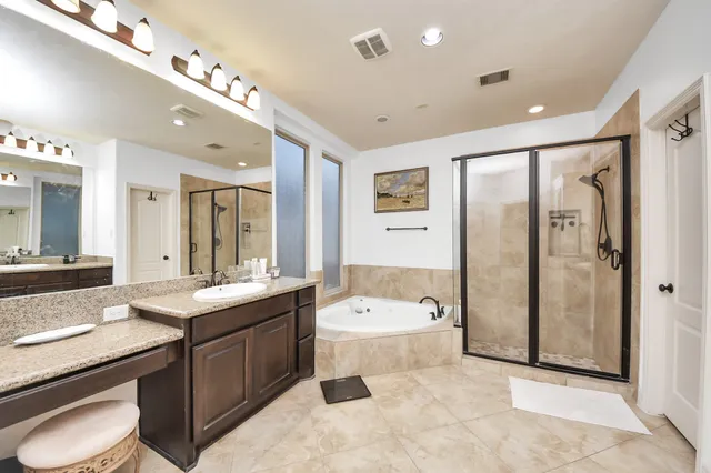 a large bathroom with a double vanity sink a large mirror and a bathtub