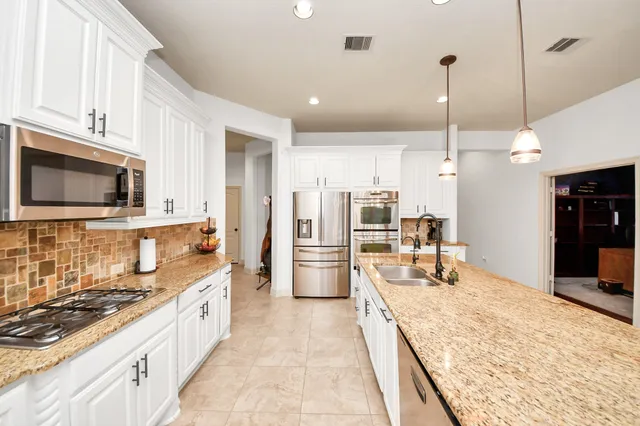 a large kitchen with stainless steel appliances kitchen island granite countertop a stove a refrigerator a oven and a sink with granite countertops