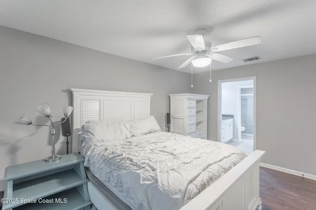 a large bed sitting in a bedroom and chandelier fan
