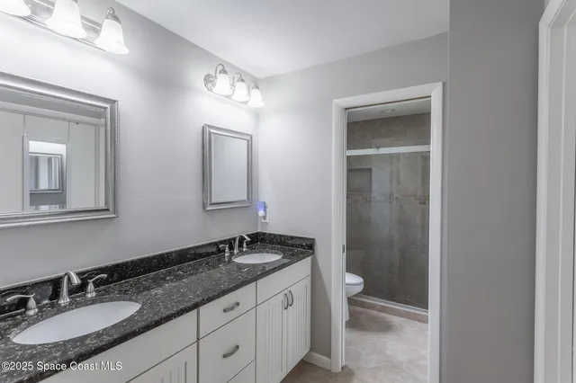 a bathroom with a granite countertop sink toilet a mirror and shower
