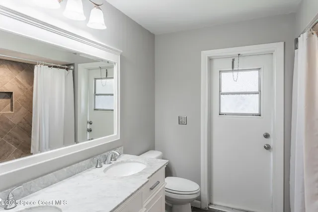 a bathroom with a granite countertop sink toilet a mirror and shower