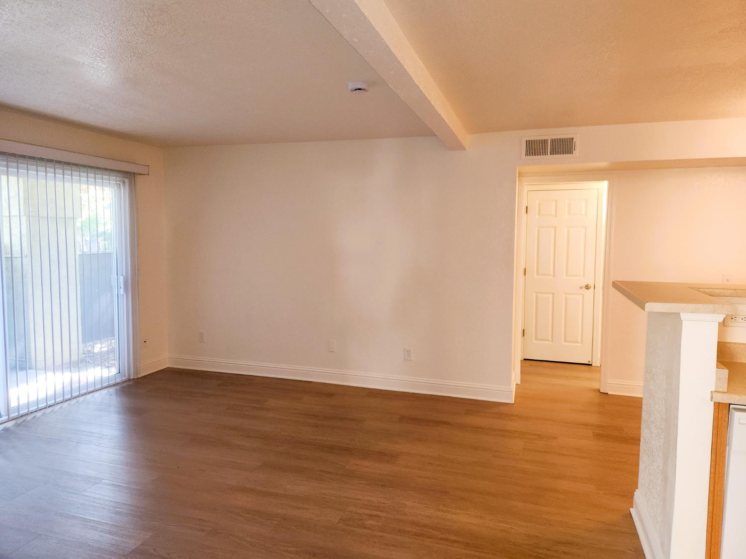 2909 Huntington Boulevard, Unit 105 Fresno, CA 93721 - Photo 2 of 7 a view of an empty room with wooden floor and a window