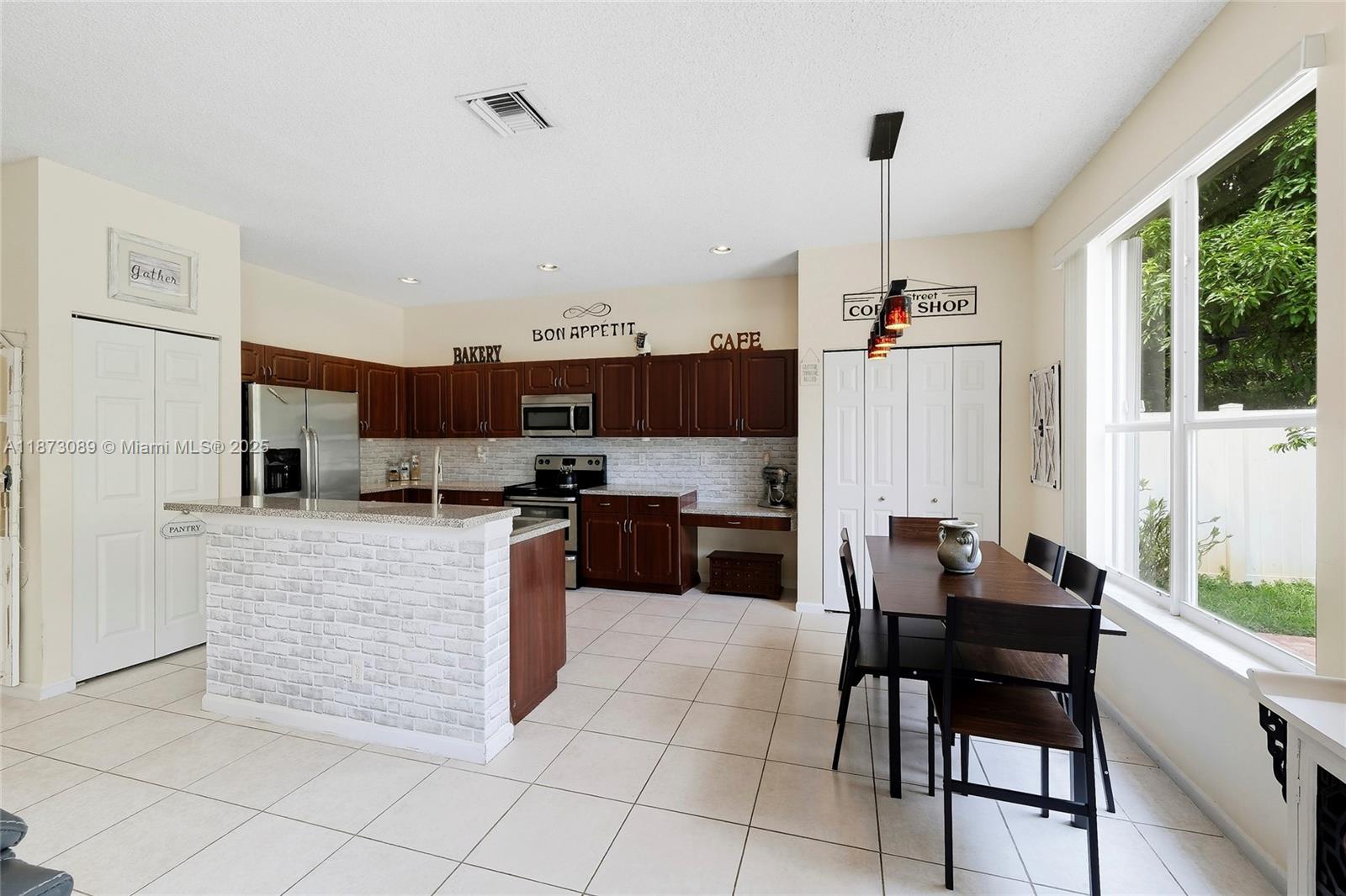 15025 Southwest 19th Court Miramar, FL 33027 - Photo 6 of 28 a kitchen with stainless steel appliances kitchen island granite countertop a table and chairs in it