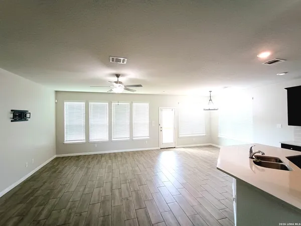 a view of an empty room with a window and wooden floor