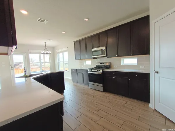 a open kitchen with kitchen island a sink dishwasher a stove and a refrigerator with wooden floor