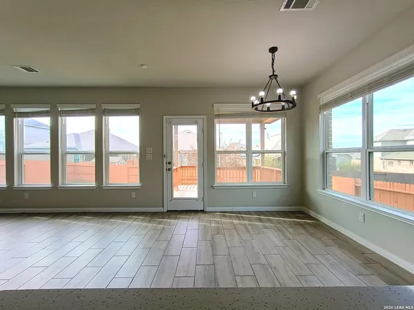 a view of empty room with wooden floor and fan