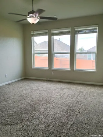 en empty room with windows and ceiling fan