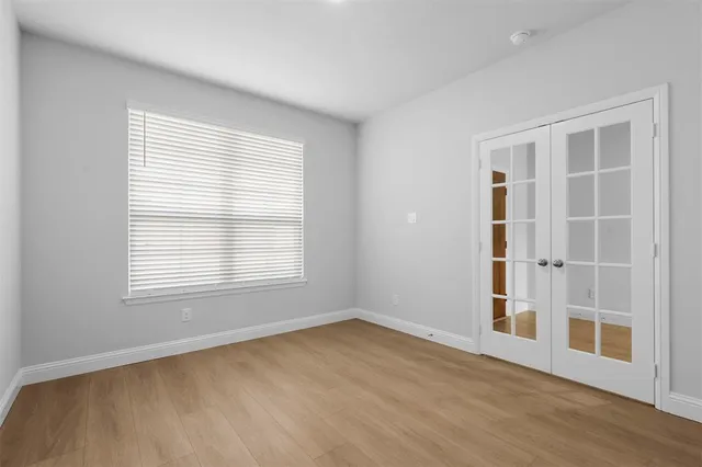 a view of an empty room with wooden floor and windows