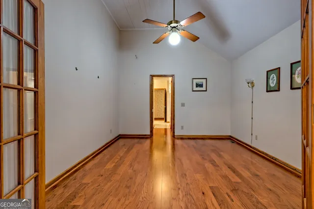 a view of empty room with wooden floor and fan