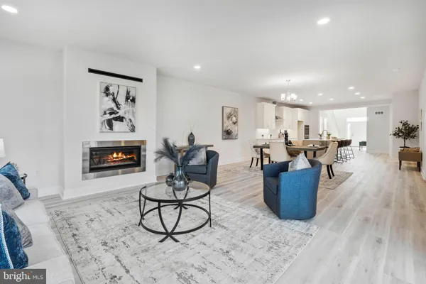 a living room with furniture kitchen view and a wooden floor