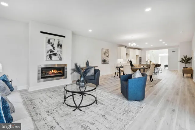 a living room with furniture kitchen view and a wooden floor