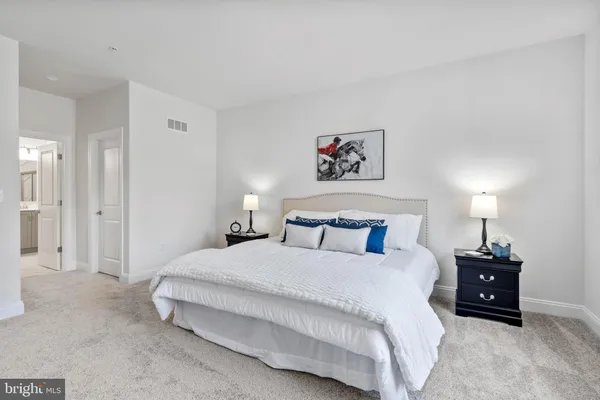 a spacious bedroom with a bed and a lamp