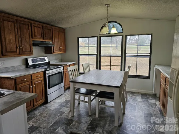 a kitchen with stainless steel appliances granite countertop a stove a sink dishwasher a dining table and chairs with wooden floor
