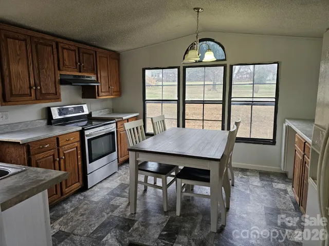 a kitchen with stainless steel appliances granite countertop a stove a sink dishwasher a dining table and chairs with wooden floor