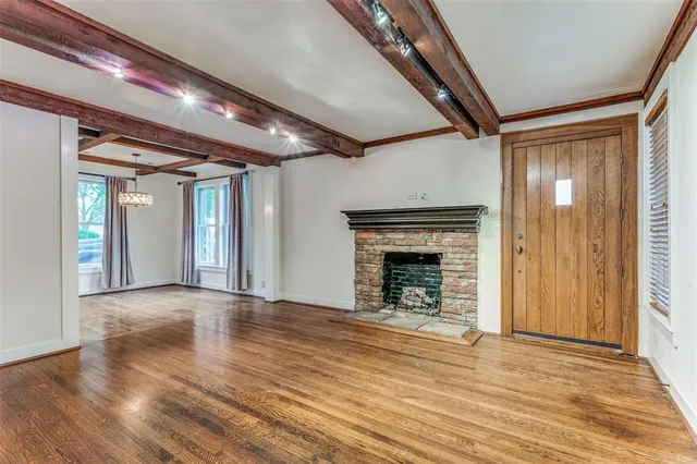 a view of an empty room with wooden floor fireplace and a window