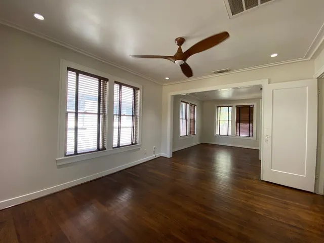 a view of an empty room with wooden floor and a window