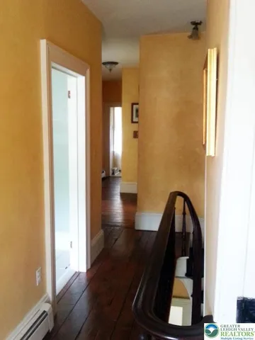 a view of a hallway with wooden floor and stairs
