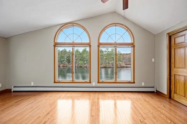 a view of an empty room with window and wooden floor