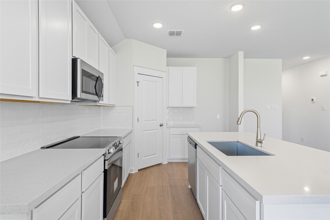 116 Crow Vly Drive Jarrell, TX 76537 - Photo 3 of 14 Kitchen with stainless steel appliances, light wood-style floors, a center island with sink, recessed lighting, and tasteful backsplash