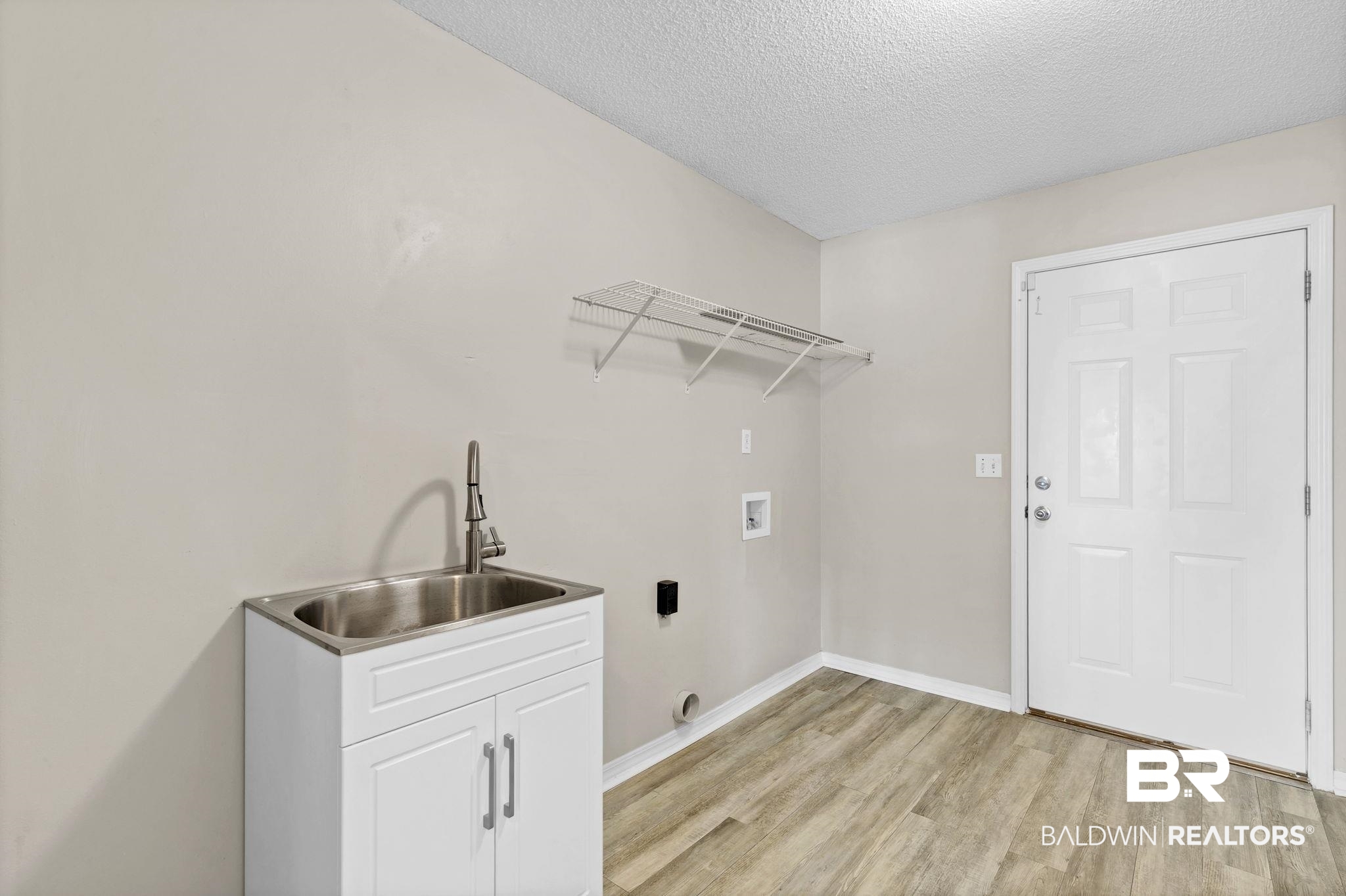 10238 Grove Drive Fairhope, AL 36532 - Photo 28 of 39 Clothes washing area featuring a textured ceiling, hookup for a washing machine, a sink, cabinet space, and light wood finished floors