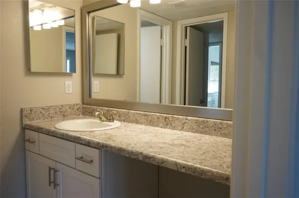 a bathroom with a granite countertop sink and a mirror