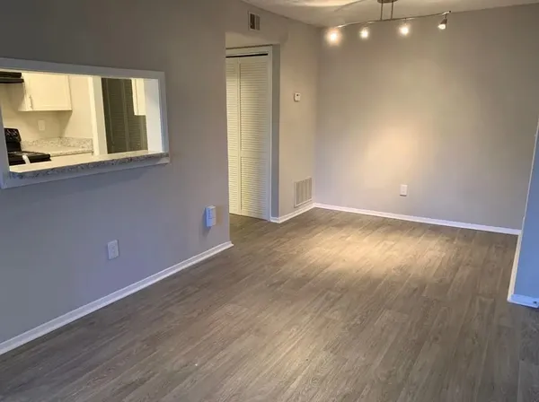 an empty room with wooden floor and windows