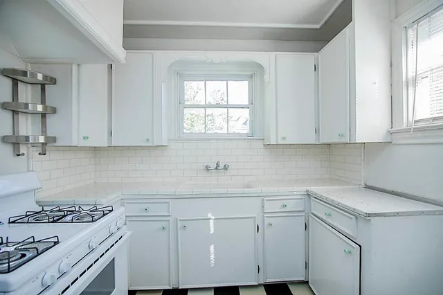 a kitchen with white cabinets appliances a sink and a window