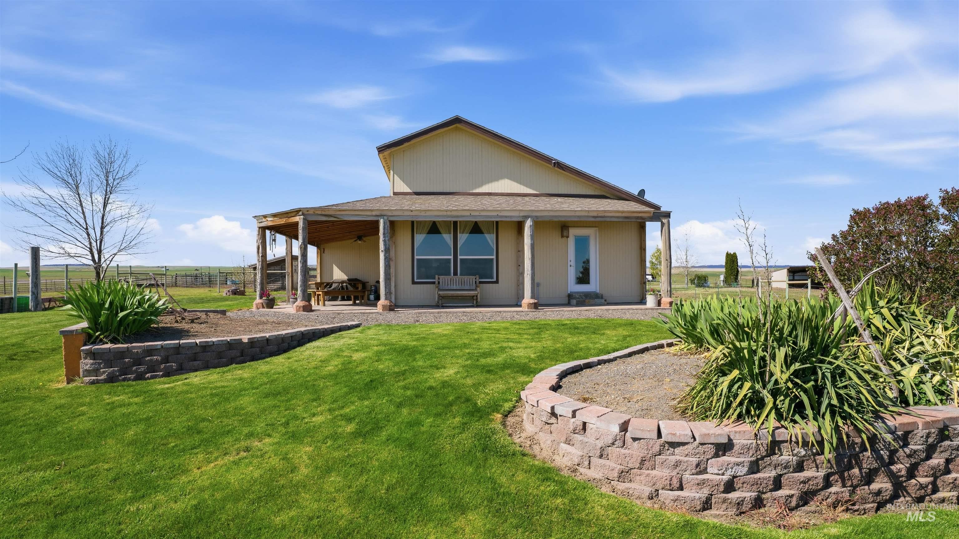 Rear exterior featuring a covered patio with exposed wood columns, a light-colored stucco finish, and a shingled roof